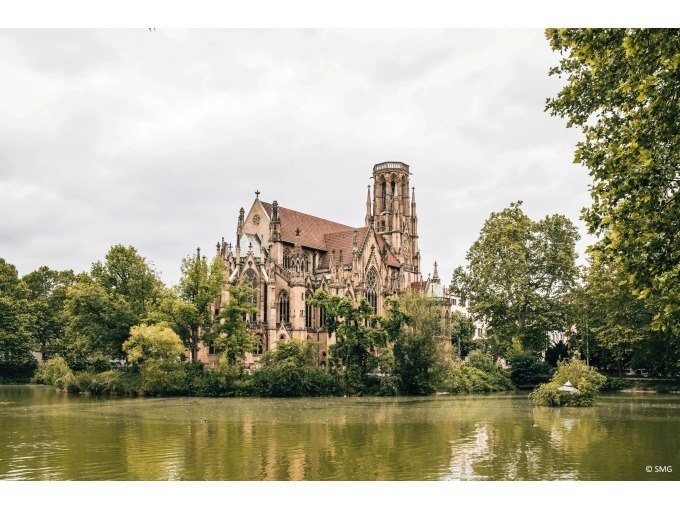 Eine gotische Kirche steht malerisch an einem See, umgeben von &uuml;ppigem Gr&uuml;n und B&auml;umen unter einem bew&ouml;lkten Himmel., &copy; Stuttgart Marketing GmbH
