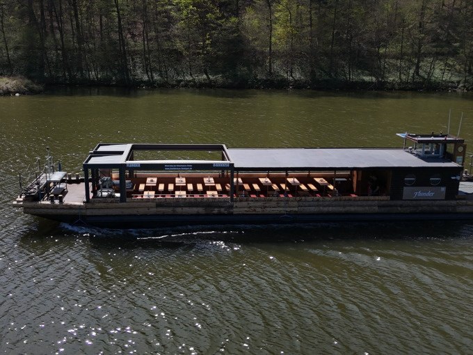 Ein Flussschiff mit offenen Sitzbereichen fährt auf einem Fluss, umgeben von Bäumen., © Cool-Tours StattReisen Ein Flussschiff mit offenen Sitzbereichen fährt auf einem Fluss, umgeben von Bäumen., © Cool-Tours StattReisen