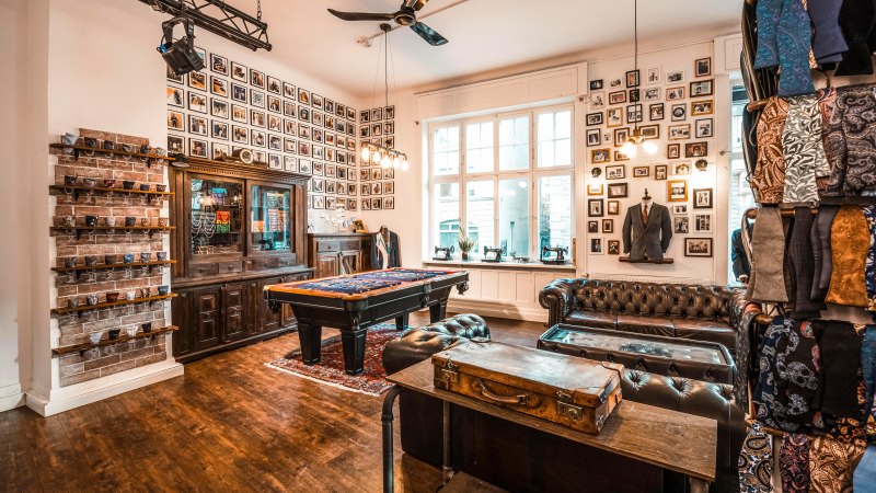 A stylish salesroom with leather sofas, a pool table, vintage décor and fabric patterns on the walls., © Mr. Ash Tailor Store, Stuttgart A stylish salesroom with leather sofas, a pool table, vintage décor and fabric patterns on the walls., © Mr. Ash Tailor Store, Stuttgart
