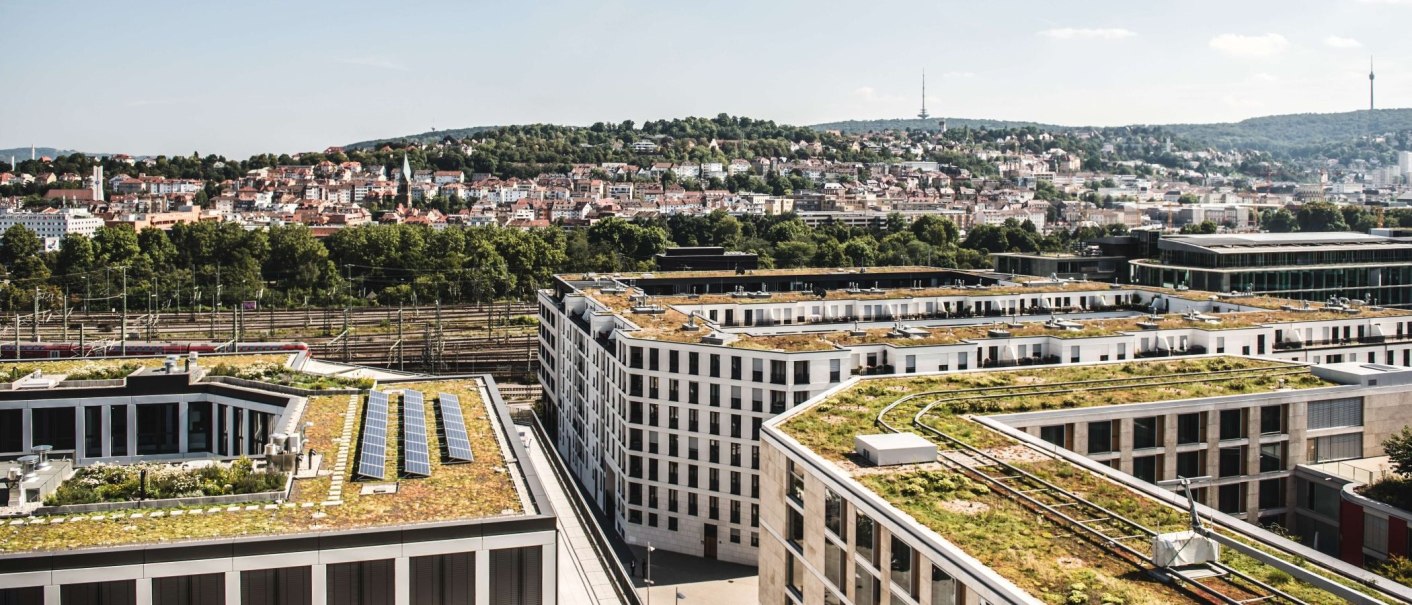 Moderne Gebäude mit begrünten Dächern im Europaviertel, dahinter eine Stadtlandschaft mit Hügeln und einem Fernsehturm., © Romeo Felsenreich Moderne Gebäude mit begrünten Dächern im Europaviertel, dahinter eine Stadtlandschaft mit Hügeln und einem Fernsehturm., © Romeo Felsenreich