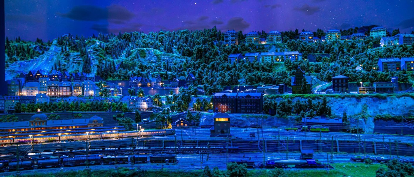 A detailed model landscape at night with illuminated buildings and a railroad in the foreground., &copy; Stuttgart-Marketing GmbH, Sarah Schmid