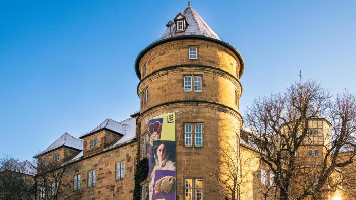 The Old Palace in Stuttgart under a clear sky. An advertising banner adorns the fa&ccedil;ade. The sun shines through the bare trees., &copy; Stuttgart-Marketing GmbH, Sarah Schmid