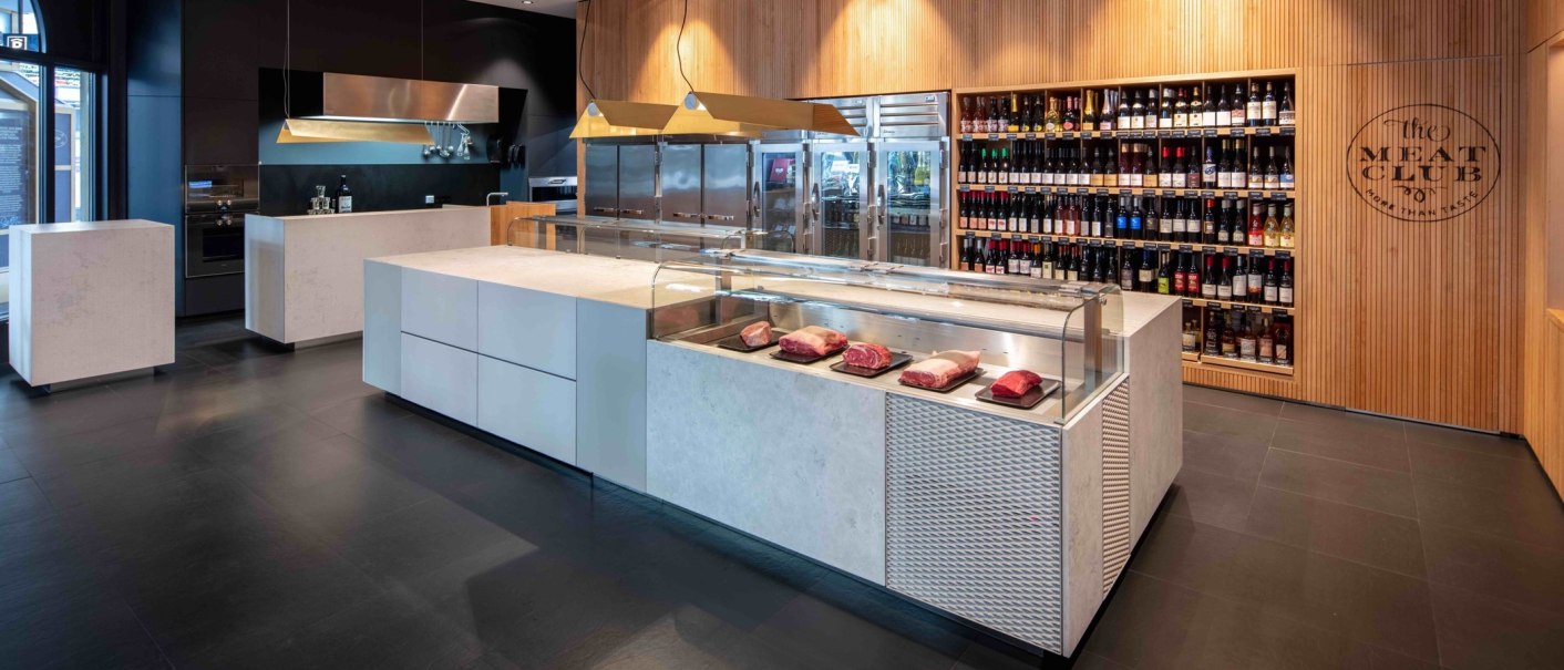 Modernes Fleischgesch&auml;ft mit Theke, auf der Fleischst&uuml;cke liegen. Im Hintergrund ein Regal mit Weinflaschen. Holzverkleidung und stilvolle Einrichtung., &copy; Meat Club, Stuttgart