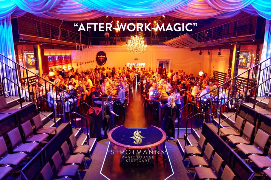 Veranstaltungsraum mit Gästen an Tischen, warm beleuchtet, Kronleuchter und Bühne. Schriftzug 'AFTER-WORK-MAGIC' und 'STROTMANNS' sichtbar., © Strotmanns Magic Lounge Veranstaltungsraum mit Gästen an Tischen, warm beleuchtet, Kronleuchter und Bühne. Schriftzug 'AFTER-WORK-MAGIC' und 'STROTMANNS' sichtbar., © Strotmanns Magic Lounge