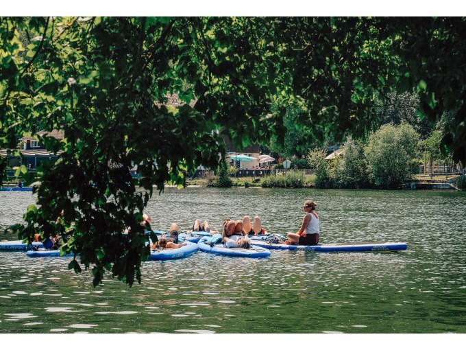 Group of people doing yoga on SUP boards on a lake surrounded by green trees., &copy; Cool-Tours StattReisen