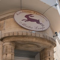Sign of the pastry shop 'Meister Lampe' with a jumping rabbit, mounted on a building facade., © SMG Stuttgart Marketing GmbH - Sarah Schmid Sign of the pastry shop 'Meister Lampe' with a jumping rabbit, mounted on a building facade., © SMG Stuttgart Marketing GmbH - Sarah Schmid