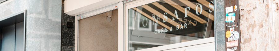 Entrance to a café with the inscription 'ConSafos Café & Bar' on the glass door. Next to it, a wall with stickers., © SMG Stuttgart Marketing GmbH - Sarah Schmid