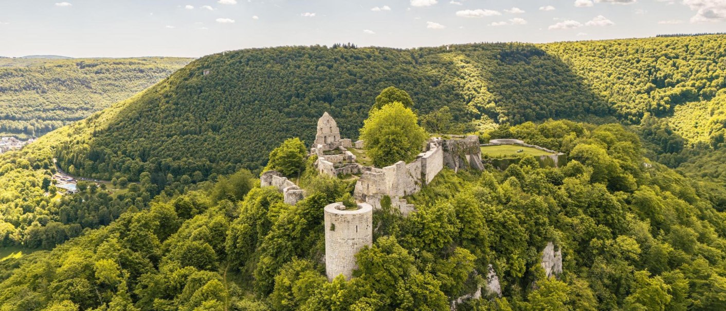 The Hohenurach castle ruins sit atop a wooded hill, surrounded by lush nature and rolling hills beneath a clear sky., © SMG Stuttgart Marketing GmbH - Sarah Schmid The Hohenurach castle ruins sit atop a wooded hill, surrounded by lush nature and rolling hills beneath a clear sky., © SMG Stuttgart Marketing GmbH - Sarah Schmid