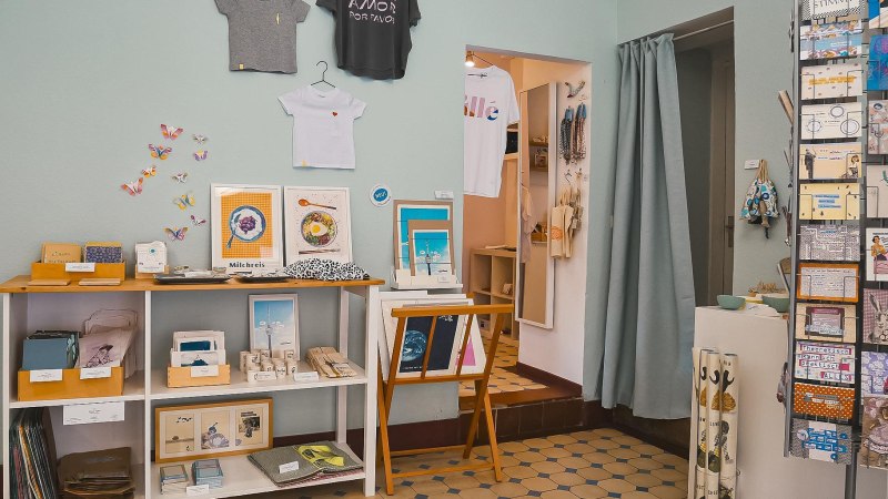 Ein Atelier mit Kunstwerken, T-Shirts an der Wand, bunten Karten und Dekorationen. Regale zeigen verschiedene kreative Produkte., © Vogelsangatelier, Stuttgart Ein Atelier mit Kunstwerken, T-Shirts an der Wand, bunten Karten und Dekorationen. Regale zeigen verschiedene kreative Produkte., © Vogelsangatelier, Stuttgart