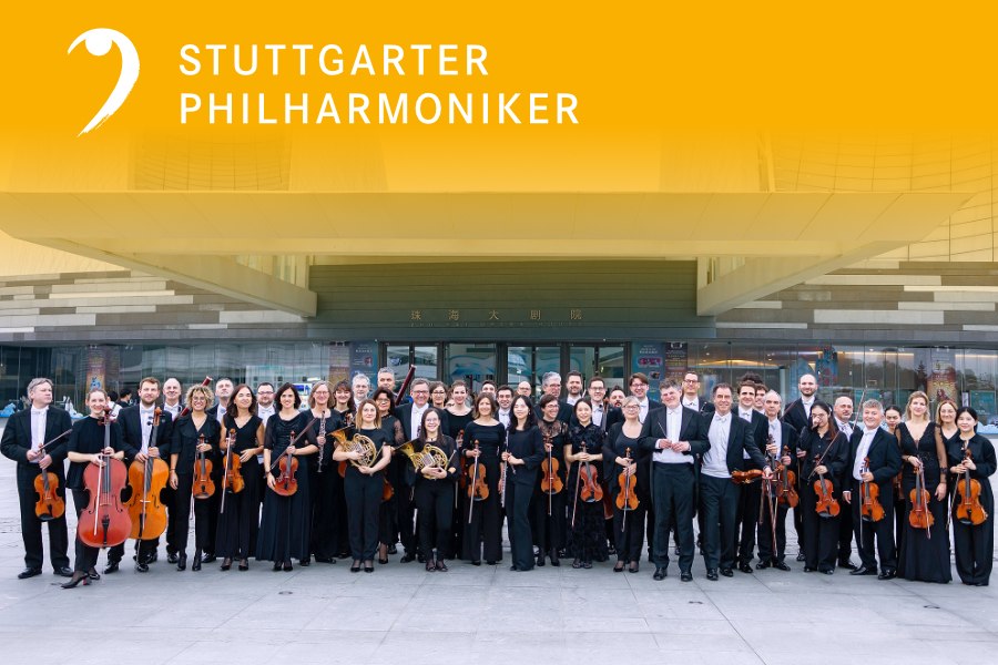 Die Stuttgarter Philharmoniker posieren mit ihren Instrumenten vor einem modernen Gebäude. Ein gelbes Banner mit ihrem Namen ist oben zu sehen., © Juan Carlos Rivas Perretta, Stuttgarter Philharmoniker