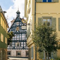 A view of a historic half-timbered house in Bad Überkingen, framed by colorful buildings, the town hall, and a tree in the foreground., © SMG Stuttgart Marketing GmbH - Sarah Schmid A view of a historic half-timbered house in Bad Überkingen, framed by colorful buildings, the town hall, and a tree in the foreground., © SMG Stuttgart Marketing GmbH - Sarah Schmid