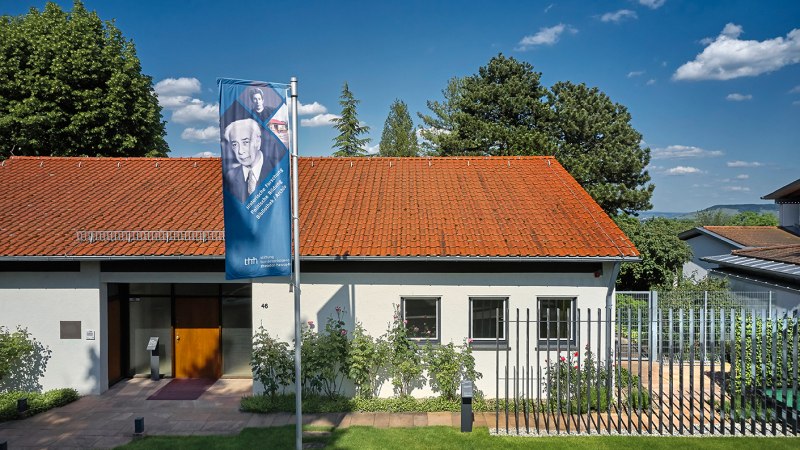 The Theodor Heuss House with a red tiled roof and a flag in front of it. It is surrounded by trees and the sky is blue with a few clouds., &copy; Theodor-Heuss-Haus/Studio Olaf Becker