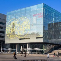 The Stuttgart Art Museum with its striking glass cube on Schlossplatz. A colorful sculpture stands in the foreground, surrounded by modern buildings., &copy; Stuttgart-Marketing GmbH, Sarah Schmid