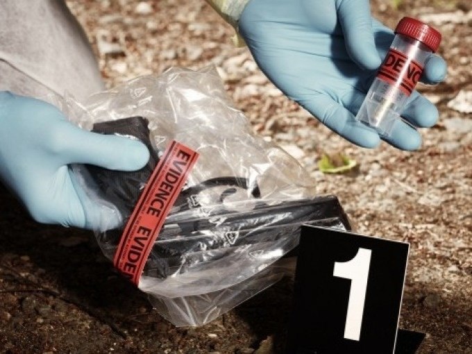 Crime scene with evidence: A pistol in a bag and a sample tube are examined by gloved hands, marked with the number 1., &copy; Cool-Tours StattReisen