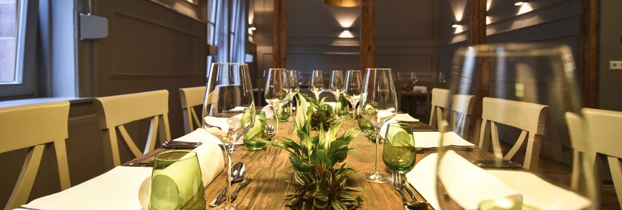 A stylishly laid dining table with wine glasses, green glasses and plants as decoration in an elegant room., © Classic Rock Café Gastronomie- Betriebs GmbH A stylishly laid dining table with wine glasses, green glasses and plants as decoration in an elegant room., © Classic Rock Café Gastronomie- Betriebs GmbH