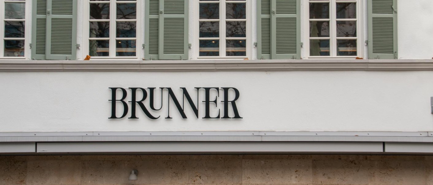 Lettering on the facade of the Brunner restaurant with serifs. Above it, lattice windows with green shutters., &copy; SMG, Sarah Schmid