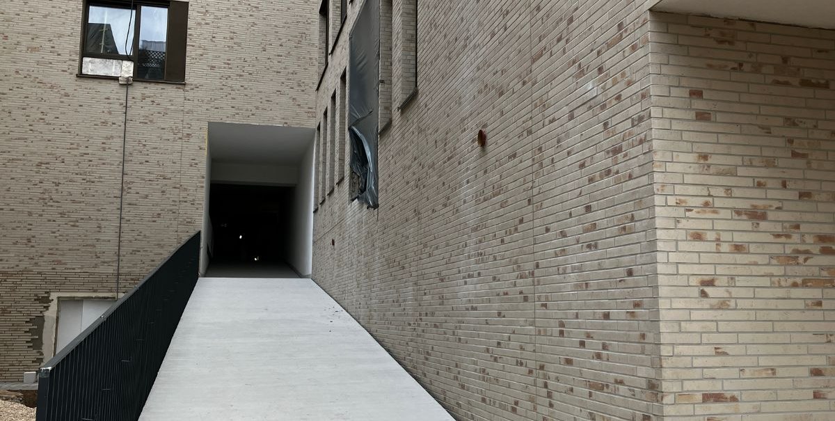 Eine weiße Rampe führt zu einem überdachten Eingang zwischen hohen Backsteinwänden. Links ist ein schwarzes Geländer., © Stadt Esslingen am Neckar Eine weiße Rampe führt zu einem überdachten Eingang zwischen hohen Backsteinwänden. Links ist ein schwarzes Geländer., © Stadt Esslingen am Neckar