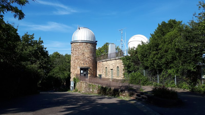 Eine Sternwarte mit runder Kuppel und Eingang, umgeben von Bäumen und blauem Himmel., © SMG Eine Sternwarte mit runder Kuppel und Eingang, umgeben von Bäumen und blauem Himmel., © SMG