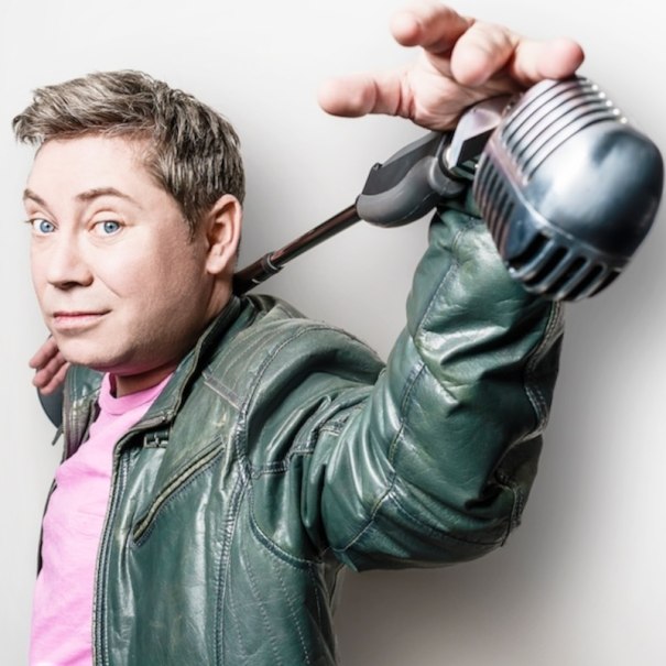 Person in grüner Lederjacke hält ein Mikrofon lässig über der Schulter und schaut in die Kamera., © Renitenztheater Stuttgart e.V.