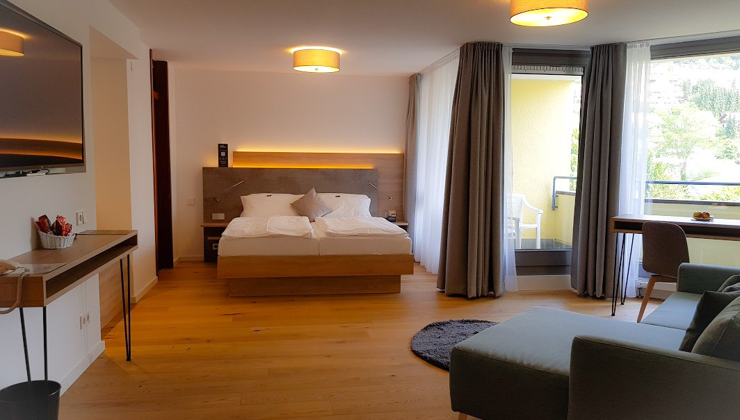 Moderne Juniorsuite mit Doppelbett, Sofa, Schreibtisch und Balkon. Helle Holzböden und große Fenster sorgen für viel Licht., © ©hotel-graf-eberhard.de