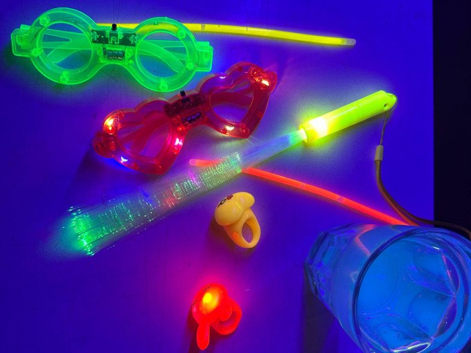 Leuchtende Brillen, Ringe und ein Glas Wasser strahlen in bunten Farben unter Schwarzlicht., © Cool-Tours StattReisen Leuchtende Brillen, Ringe und ein Glas Wasser strahlen in bunten Farben unter Schwarzlicht., © Cool-Tours StattReisen