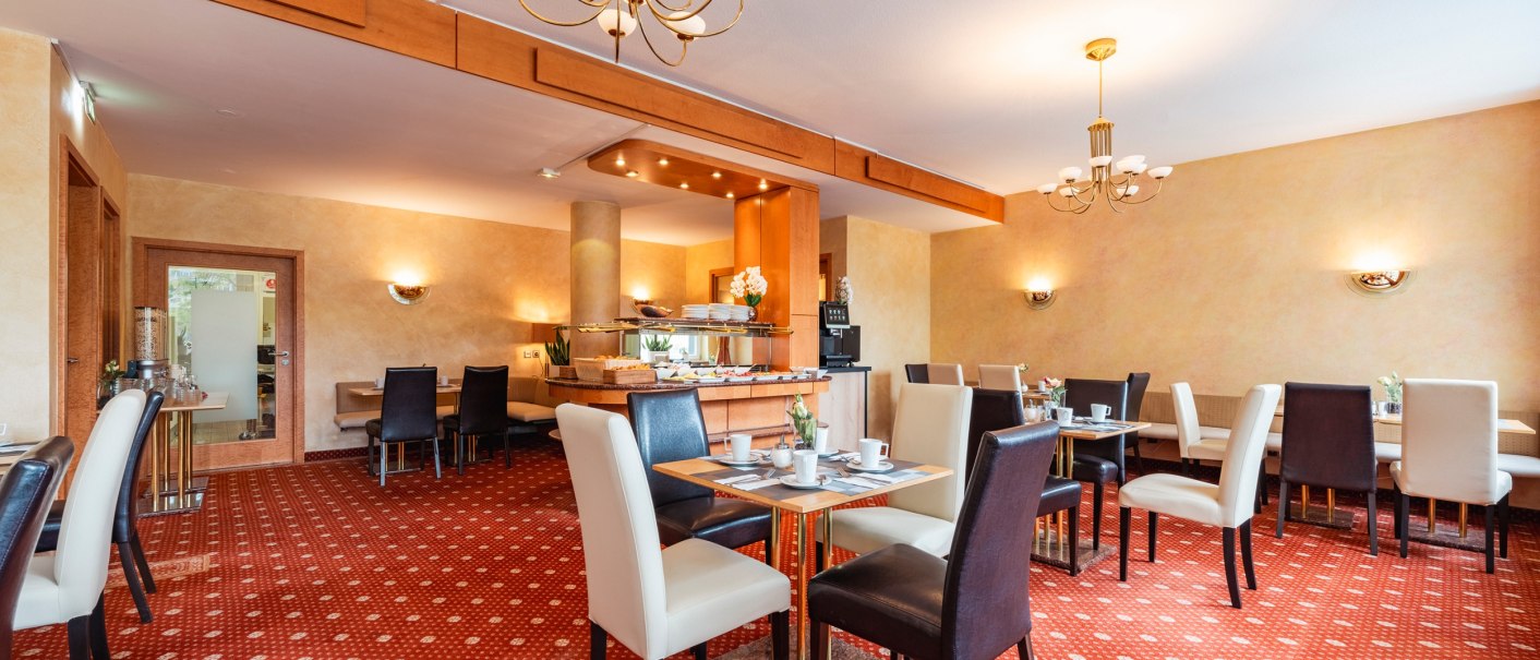 Eleganter Frühstücksraum mit gedeckten Tischen, roten Teppichboden und Kronleuchtern. Buffetbereich im Hintergrund., © PLAZA INN Rieker Stuttgart Hauptbahnhof Eleganter Frühstücksraum mit gedeckten Tischen, roten Teppichboden und Kronleuchtern. Buffetbereich im Hintergrund., © PLAZA INN Rieker Stuttgart Hauptbahnhof