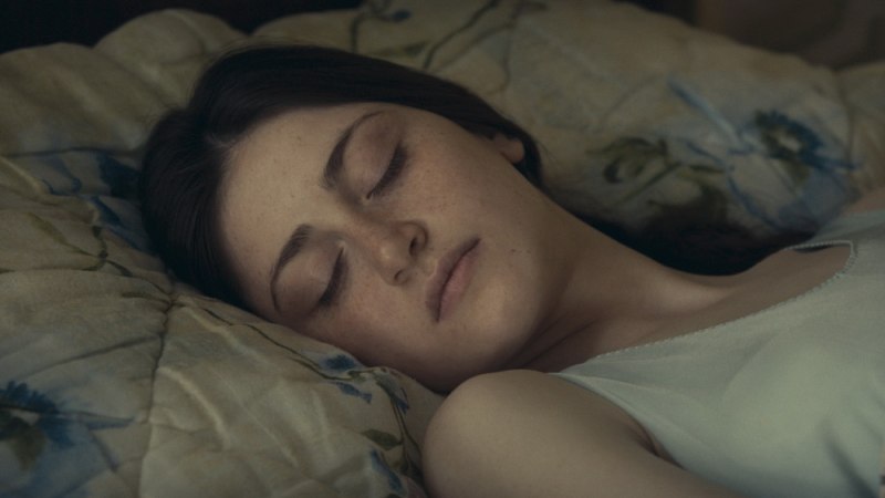 Eine Frau schläft friedlich auf einem gemusterten Kissen. Ihr Gesicht ist entspannt und die Augen sind geschlossen., © Grandfilm Eine Frau schläft friedlich auf einem gemusterten Kissen. Ihr Gesicht ist entspannt und die Augen sind geschlossen., © Grandfilm