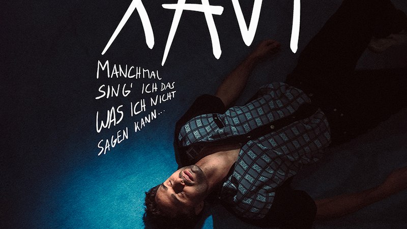 Ein Mann liegt auf blauem Boden, umgeben von Schriftz&uuml;gen: 'XAVI', 'Manchmal sing' ich das, was ich nicht sagen kann...', 'TOUR2026'., &copy; Music Circus Concertb&uuml;ro GmbH & Co. KG