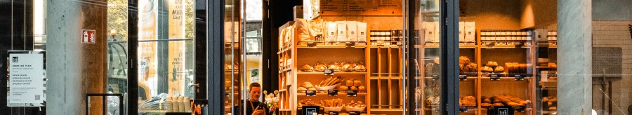 Entrance to a bakery with a glass front. Shelves with baked goods can be seen inside. 'Time for bread' is written above the door., &copy; Zeit f&uuml;r Brot Stuttgart