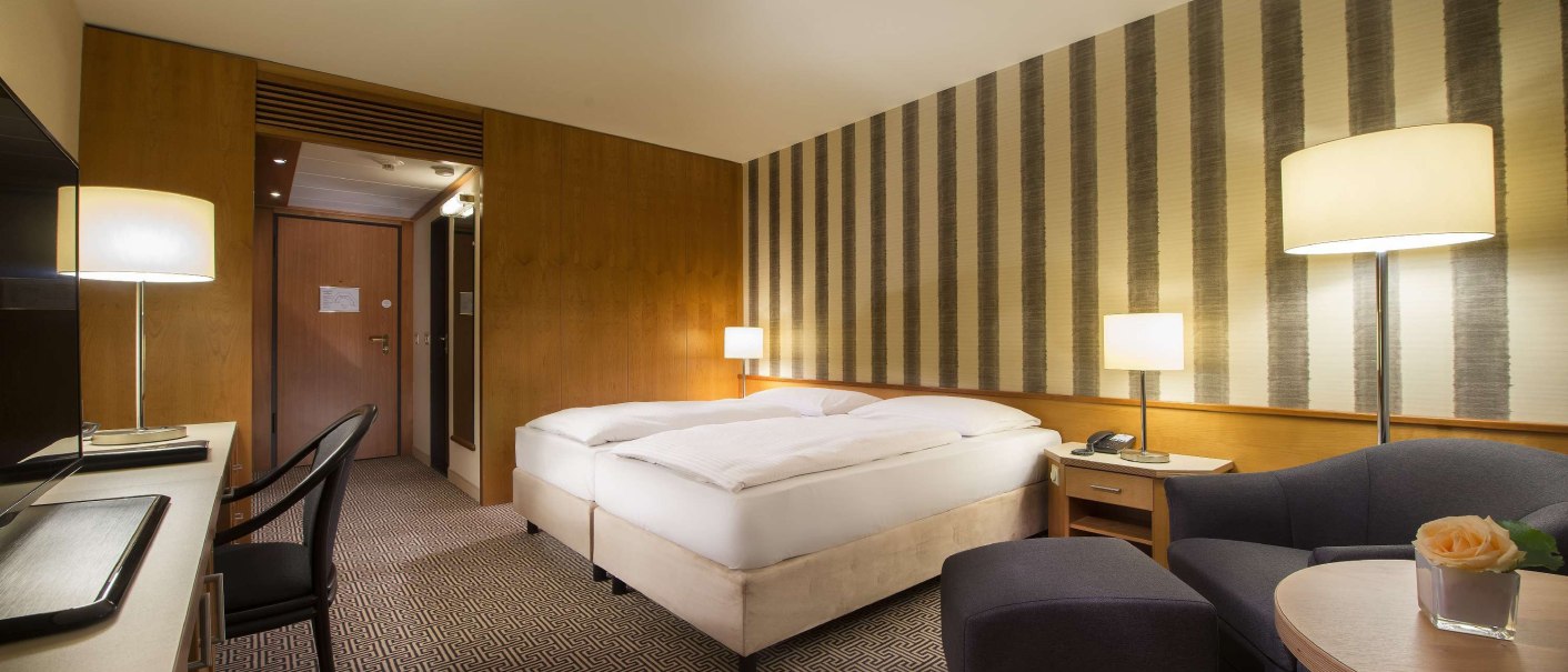 Modernes Hotelzimmer mit Doppelbett, Schreibtisch, Sessel und stilvoller Beleuchtung. Die Wände sind mit Streifenmuster tapeziert., © Maritim Hotelgesellschaft mbH Modernes Hotelzimmer mit Doppelbett, Schreibtisch, Sessel und stilvoller Beleuchtung. Die Wände sind mit Streifenmuster tapeziert., © Maritim Hotelgesellschaft mbH