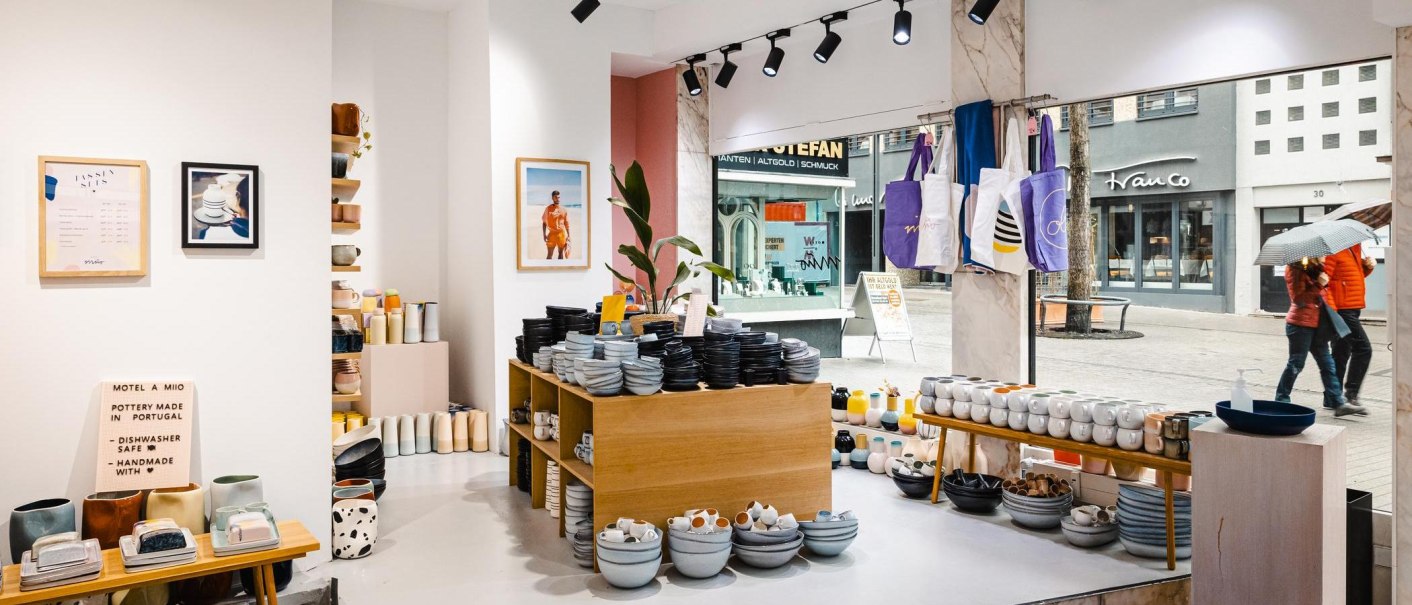 Keramikladen mit Regalen voller Geschirr, Tassen und Vasen. An der Wand hängen Bilder und Taschen. Durch das Schaufenster sieht man eine Straße., © Stuttgart-Marketing GmbH, Sarah Schmid