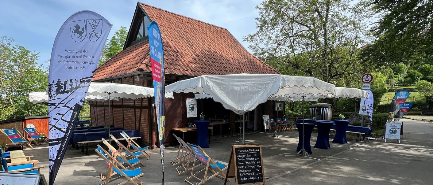 Ein Au&szlig;enbereich mit Zelt, Liegest&uuml;hlen und Tischen vor einem Fachwerkgeb&auml;ude. Schilder und Banner weisen auf eine Veranstaltung hin., &copy; Frank Nonnenmann