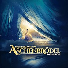 Poster für das Musical 'Drei Haselnüsse für Aschenbrödel' zeigt eine Frau in einem goldenen Kleid vor einem leuchtenden, märchenhaften Hintergrund., © links im Bild Poster für das Musical 'Drei Haselnüsse für Aschenbrödel' zeigt eine Frau in einem goldenen Kleid vor einem leuchtenden, märchenhaften Hintergrund., © links im Bild