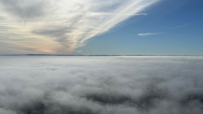 Ein beeindruckender Blick über eine dichte Wolkendecke, darüber ein klarer blauer Himmel und eine Bergsilhouette am Horizont., © SMG