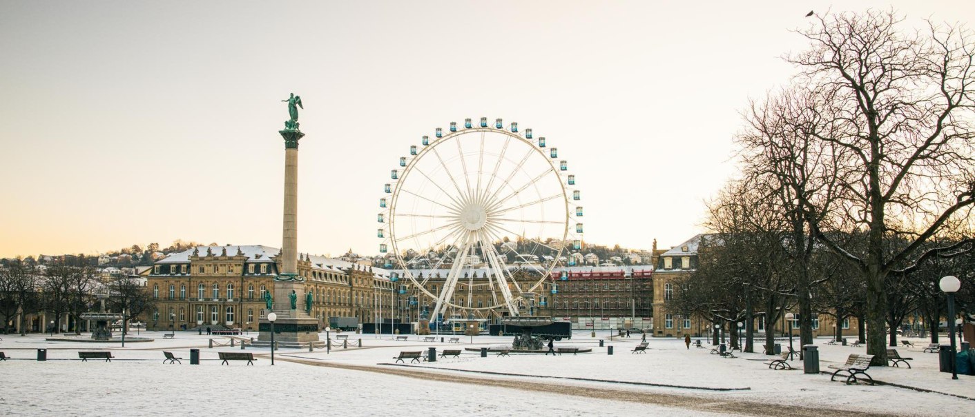 Winterlicher Schlossplatz in Stuttgart mit schneebedecktem Boden, einer hohen S&auml;ule und einem gro&szlig;en Riesenrad vor einem Schloss, im Hintergrund., &copy; Stuttgart-Marketing GmbH, Sarah Schmid