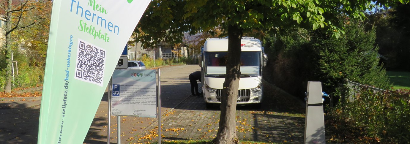Wohnmobilstellplatz in Bad &Uuml;berkingen mit einem geparkten Wohnmobil, B&auml;umen und einem Schild mit QR-Code und Informationen., &copy; Archiv Gemeinde Bad &Uuml;berkingen