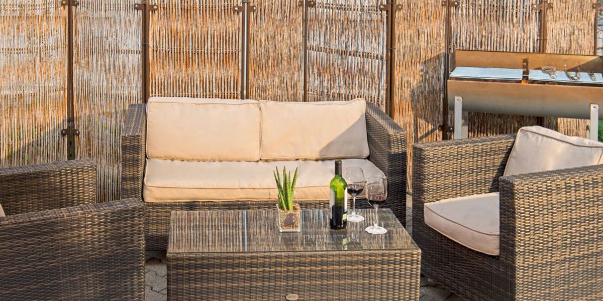 Terrasse mit Rattanmöbeln, einem Glastisch, Weingläsern und einer Weinflasche. Im Hintergrund ein Sichtschutz aus Bambus und ein Grill., © NH Stuttgart Sindelfingen Terrasse mit Rattanmöbeln, einem Glastisch, Weingläsern und einer Weinflasche. Im Hintergrund ein Sichtschutz aus Bambus und ein Grill., © NH Stuttgart Sindelfingen