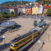 Luftaufnahme des Marienplatzes in Stuttgart. Eine gelbe Stra&szlig;enbahn f&auml;hrt vorbei, umgeben von B&auml;umen und Geb&auml;uden. Der Platz ist belebt und sonnig., &copy; Stuttgart-Marketing GmbH, Achim Mende