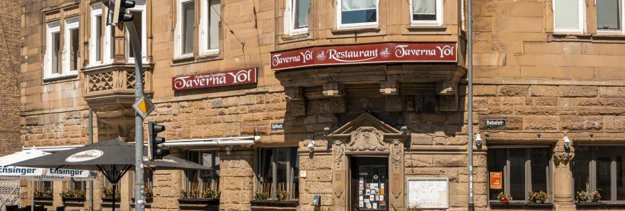 Historisches Geb&auml;ude mit Restaurant Taverna Yol, Sitzpl&auml;tze im Freien, Stra&szlig;enschilder und Ampeln. Sonniger Tag, Blumen in Fenstern., &copy; SMG, Sarah Schmid