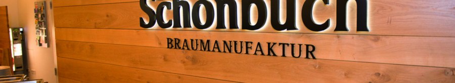Innenansicht einer Brauerei mit Buffet. An der Holzwand steht "Schönbuch Braumanufaktur". Im Vordergrund sind Speisen in Warmhaltebehältern., © Schönbuchbrauerei, Sebastian Berger