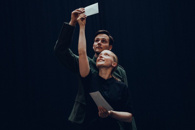 Two people are smiling and holding letters in the air. The background is dark, which makes the scene look dramatic., &copy; Festspielhaus Neuschwanstein gGmbh