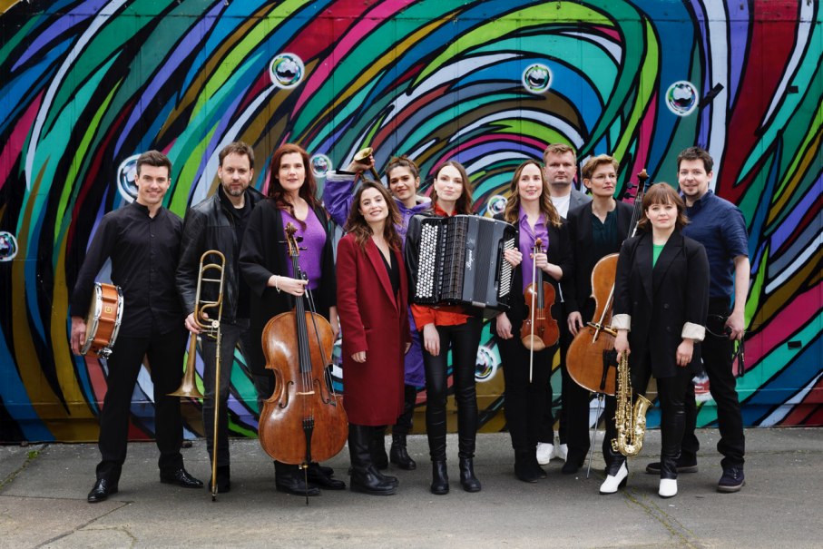 Das Ensemble LUX:NM posiert vor einer farbenfrohen Wandmalerei. Die Musiker halten verschiedene Instrumente und l&auml;cheln in die Kamera., &copy; Andrea Huyoff und Slowik