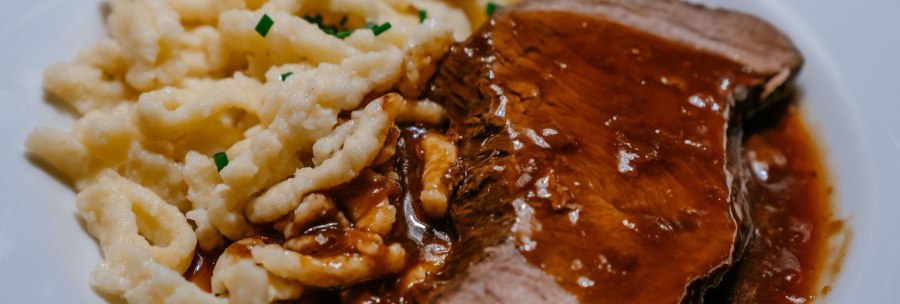 Ein Teller mit saftigem Braten in dunkler Soße, serviert mit Spätzle, garniert mit Schnittlauch., © SMG, Thomas Niedermüller Ein Teller mit saftigem Braten in dunkler Soße, serviert mit Spätzle, garniert mit Schnittlauch., © SMG, Thomas Niedermüller