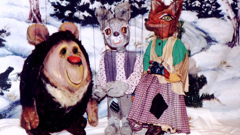 Drei Puppenfiguren, ein Bär, ein Hase und ein Fuchs, sitzen vor einem winterlichen Hintergrund mit Schnee und Bäumen., © Nellys Puppentheater Drei Puppenfiguren, ein Bär, ein Hase und ein Fuchs, sitzen vor einem winterlichen Hintergrund mit Schnee und Bäumen., © Nellys Puppentheater