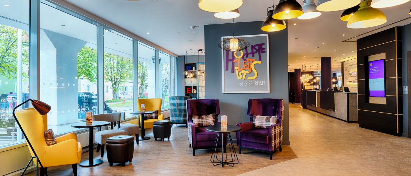 Moderne Lobby mit bunten Sesseln, gro&szlig;en Fenstern und stilvollen Lampen. Einladende Atmosph&auml;re mit einem Empfangsbereich im Hintergrund., &copy; Premier Inn Germany