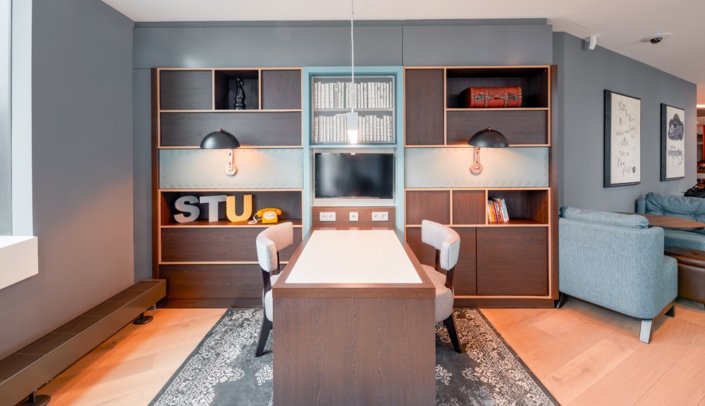 Moderner Arbeitsbereich mit Tisch, Regalen, Dekorationen und gemütlichen Sesseln in einem stilvollen Raum., © Premier Inn Moderner Arbeitsbereich mit Tisch, Regalen, Dekorationen und gemütlichen Sesseln in einem stilvollen Raum., © Premier Inn