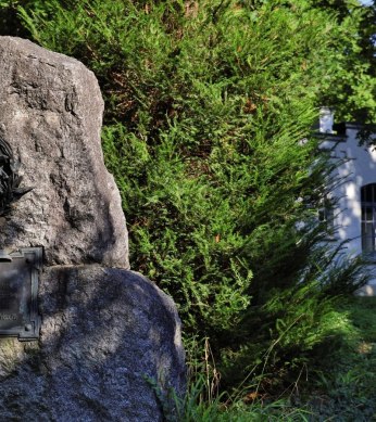 Memorial stone for Gottlieb Daimler in a green park, on the right a white building with glass windows., © Stuttgart-Marketing GmbH Achim Mende