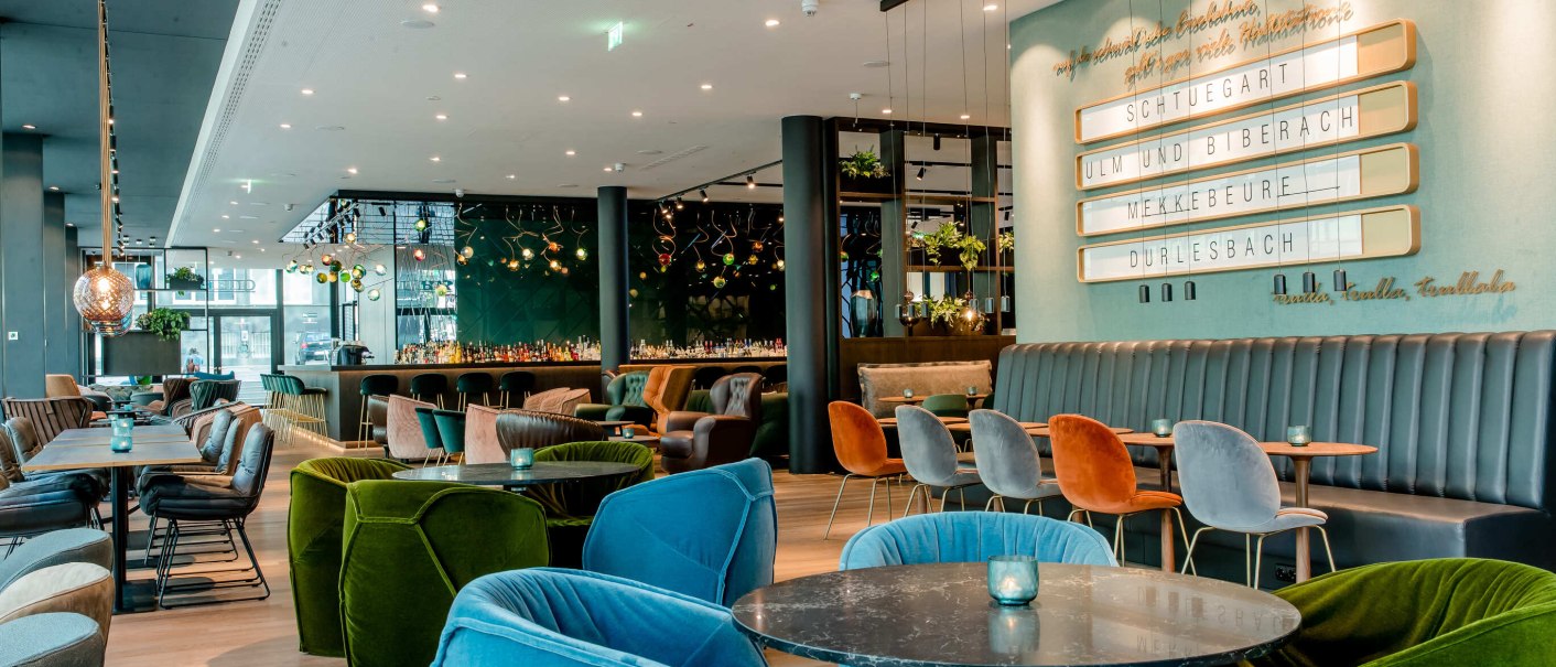 Modern restaurant with colorful armchairs, tables and stylish lighting. A blackboard on the wall shows the names of cities. Elegant and cozy atmosphere., &copy; Motel One - Stuttgart Hauptbahnhof