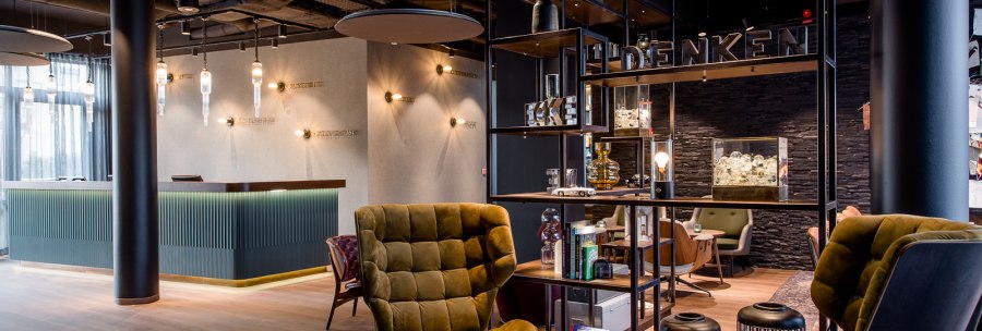 Moderne Hotellobby mit eleganten Sesseln, einem Empfangstresen und stilvoller Beleuchtung. Offenes Regal trennt Sitzbereich ab., © TOMAS Moderne Hotellobby mit eleganten Sesseln, einem Empfangstresen und stilvoller Beleuchtung. Offenes Regal trennt Sitzbereich ab., © TOMAS