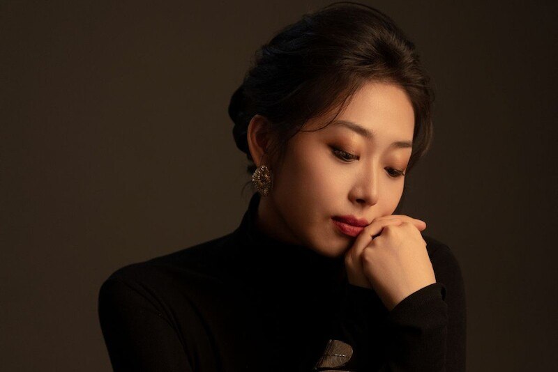 Eine Frau in einem schwarzen Rollkragenpullover schaut nachdenklich zur Seite, die Hand am Kinn gestützt. Sie trägt auffällige Ohrringe., © il Gusto Barocco - Stuttgarter Barockorchester